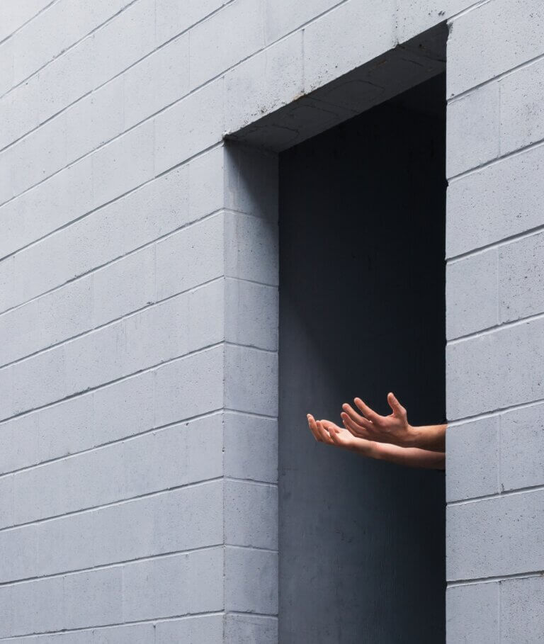 Two Hands reaching out of a doorway into the light.